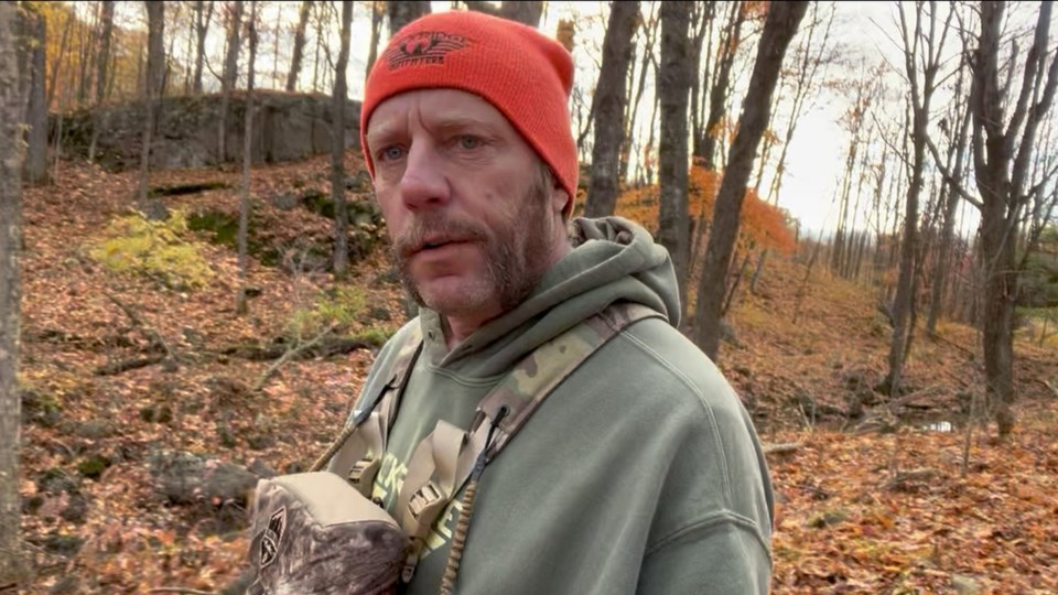 Resident in orange hunting cap standing in an autumn wooded area along the ALTO southern corridor.