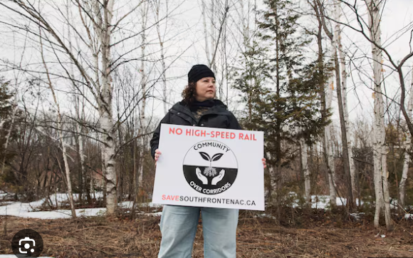 Protestor holding a No High-Speed Rail sign with the Save South Frontenac community logo.