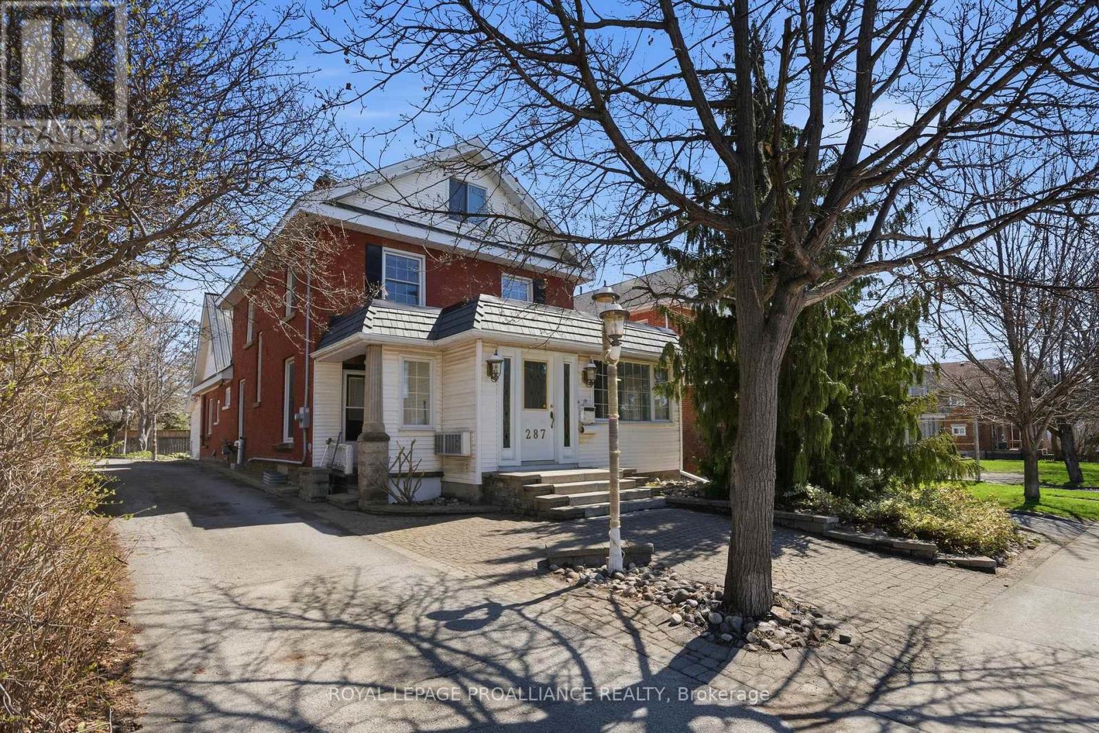 A modest detached two-storey house in a town street, numbered 287, on a typical urban lot.